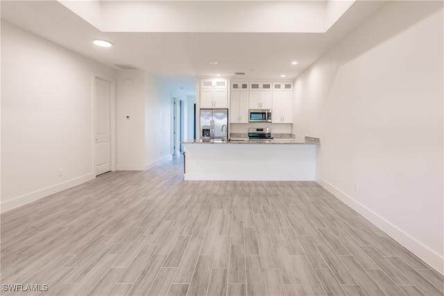 kitchen featuring kitchen peninsula, light hardwood / wood-style flooring, white cabinets, and appliances with stainless steel finishes