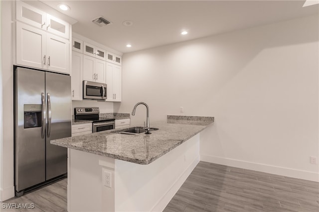 kitchen with sink, kitchen peninsula, light hardwood / wood-style flooring, white cabinetry, and stainless steel appliances