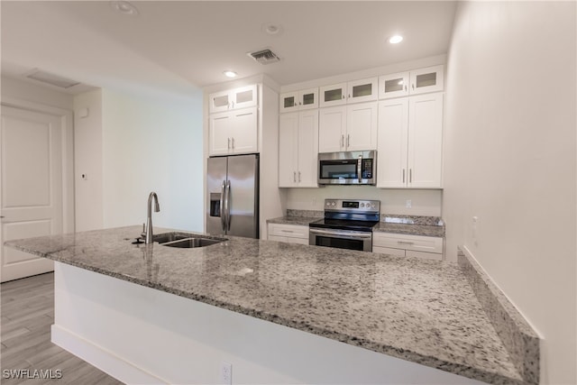 kitchen featuring light stone countertops, sink, appliances with stainless steel finishes, white cabinets, and light wood-type flooring