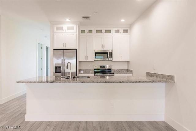 kitchen featuring stainless steel appliances, white cabinetry, and light hardwood / wood-style floors