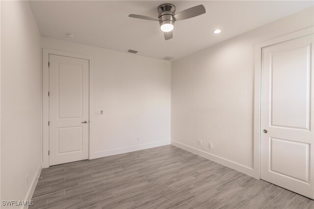 empty room with ceiling fan and light hardwood / wood-style floors