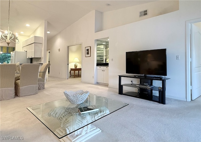 carpeted living room with high vaulted ceiling and a notable chandelier