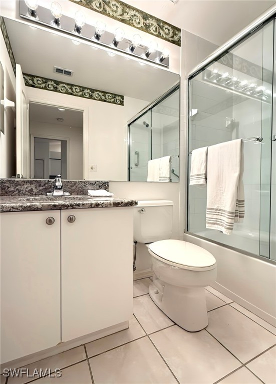 full bathroom featuring tile patterned flooring, shower / bath combination with glass door, vanity, and toilet