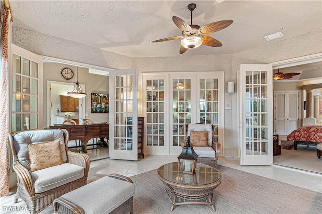 interior space featuring ceiling fan, a textured ceiling, light tile patterned floors, and french doors