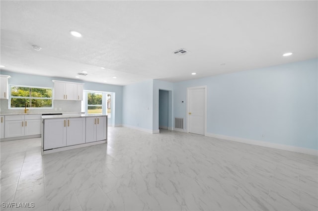 kitchen with white cabinetry, backsplash, and a kitchen island