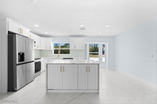 kitchen featuring stainless steel appliances, white cabinets, backsplash, and a kitchen island