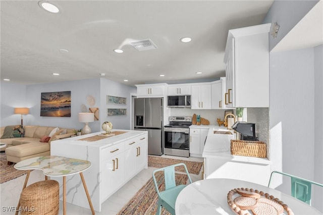 kitchen with a center island, appliances with stainless steel finishes, sink, and white cabinets