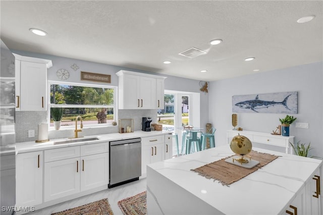 kitchen featuring plenty of natural light, dishwasher, sink, and white cabinets