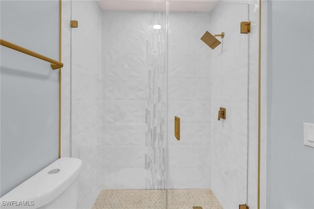 bathroom featuring toilet and a shower with shower door