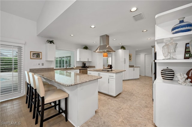 kitchen with white cabinets, dishwasher, island exhaust hood, a kitchen island, and light stone countertops