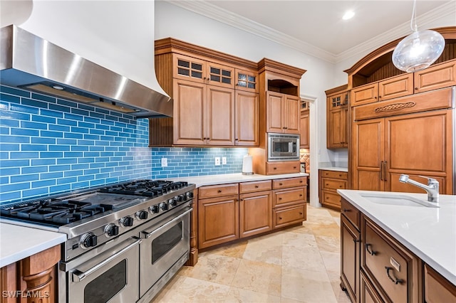 kitchen featuring sink, wall chimney range hood, built in appliances, pendant lighting, and decorative backsplash