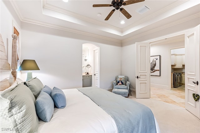 carpeted bedroom featuring a raised ceiling, ensuite bath, ceiling fan, and crown molding