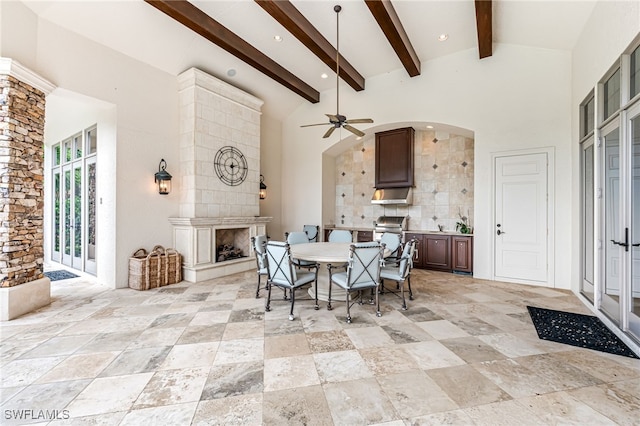 dining space featuring beamed ceiling, ceiling fan, a fireplace, and high vaulted ceiling