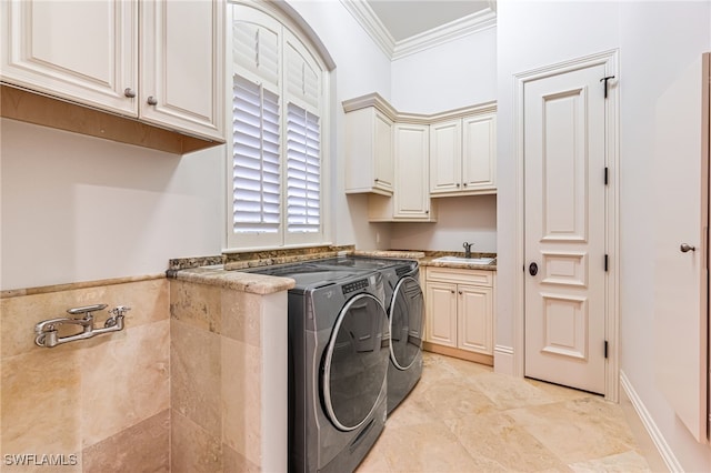 washroom with cabinets, ornamental molding, sink, and washing machine and clothes dryer