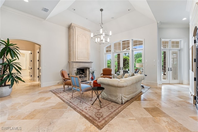 living room with a fireplace, crown molding, french doors, and a notable chandelier