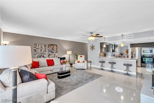 tiled living room with ceiling fan and crown molding