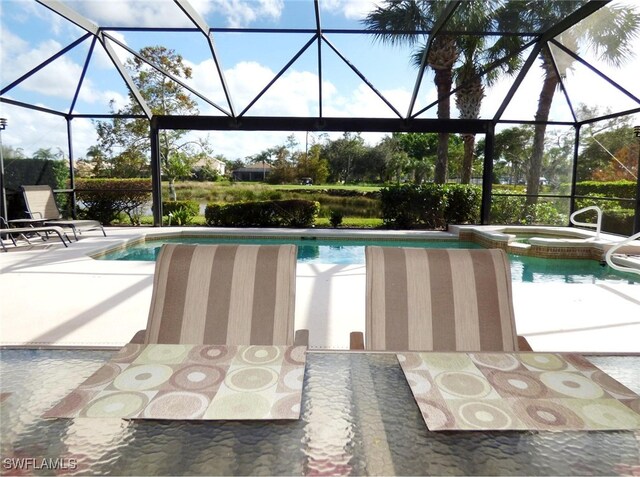 view of pool featuring glass enclosure, an in ground hot tub, and a patio