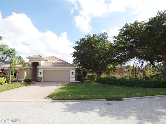 view of front facade featuring a front yard, a tiled roof, decorative driveway, and an attached garage