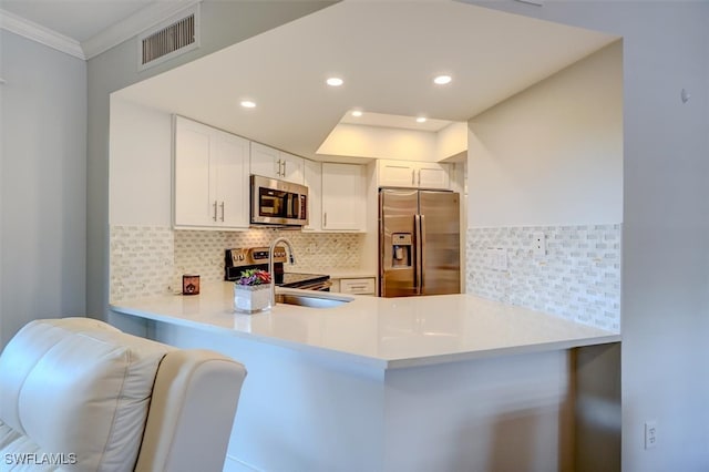 kitchen featuring white cabinetry, tasteful backsplash, kitchen peninsula, appliances with stainless steel finishes, and ornamental molding