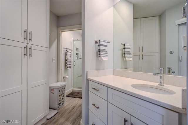 bathroom with hardwood / wood-style flooring, vanity, and an enclosed shower