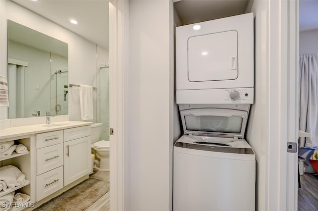 laundry area with sink, light hardwood / wood-style flooring, and stacked washer and clothes dryer