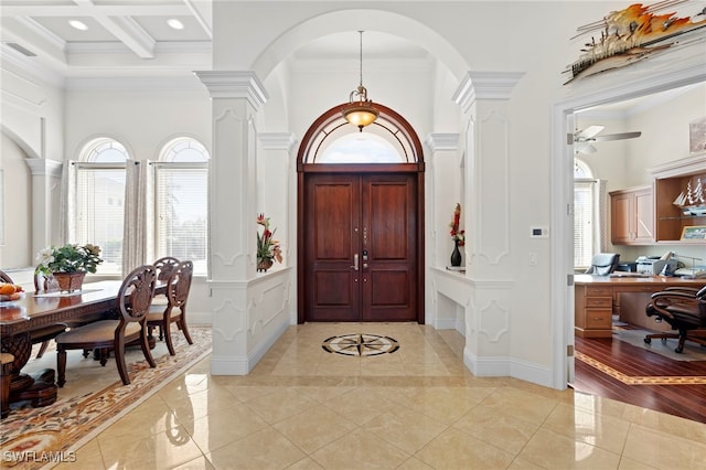 foyer with light hardwood / wood-style floors, coffered ceiling, ceiling fan, crown molding, and beam ceiling