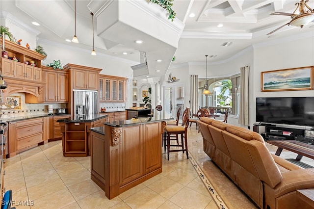 kitchen featuring hanging light fixtures, stainless steel fridge, a center island with sink, and ornamental molding