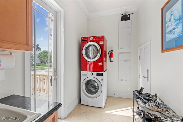 laundry room featuring ornamental molding, light tile patterned floors, and stacked washer / dryer