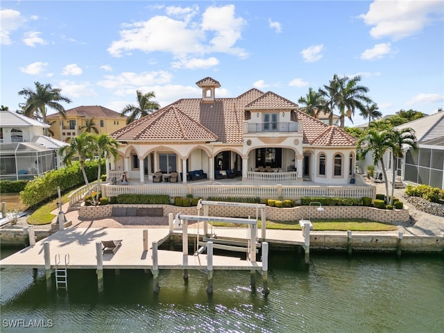 back of property with a balcony, a water view, and a patio area