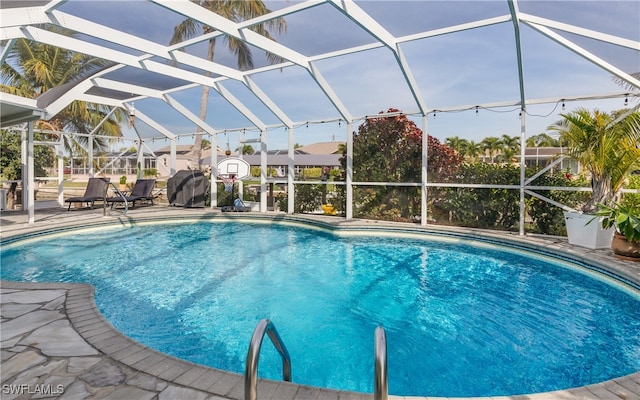 view of pool featuring glass enclosure and a patio