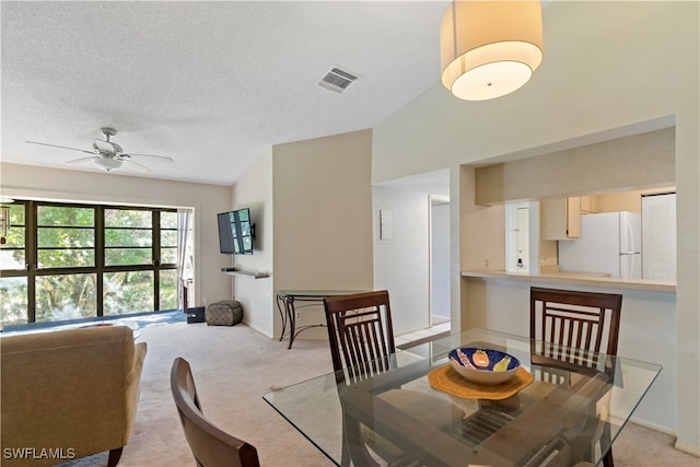 dining room featuring lofted ceiling, a textured ceiling, light colored carpet, and ceiling fan