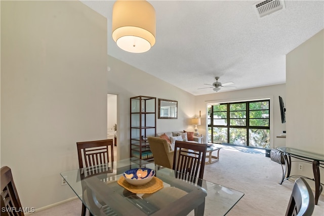 carpeted dining space featuring lofted ceiling, a textured ceiling, and ceiling fan