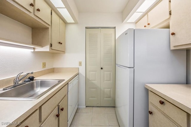 kitchen featuring white appliances, light tile patterned floors, light countertops, and a sink