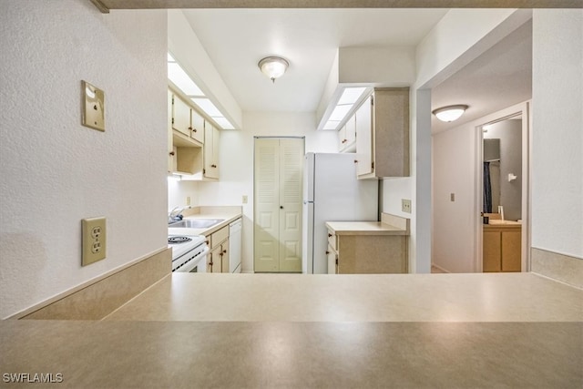 kitchen with white appliances, cream cabinetry, sink, and a skylight