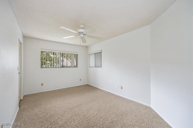 spare room with a textured ceiling, carpet flooring, and ceiling fan