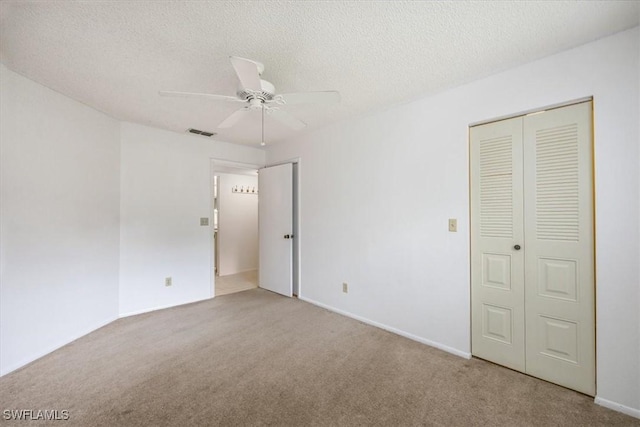 unfurnished bedroom featuring a textured ceiling, ceiling fan, carpet flooring, and visible vents