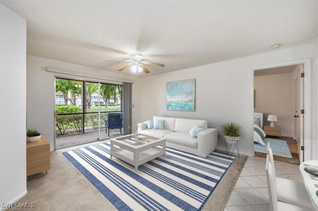 living room with a ceiling fan, a textured ceiling, and light tile patterned floors