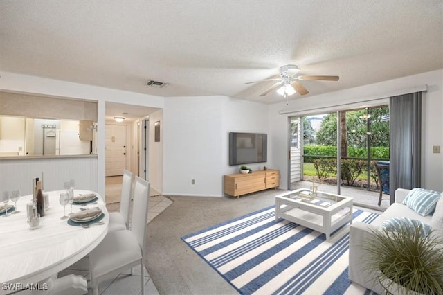 living area featuring a ceiling fan, carpet, visible vents, and a textured ceiling