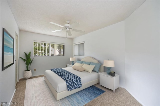 carpeted bedroom with a textured ceiling, a ceiling fan, and baseboards