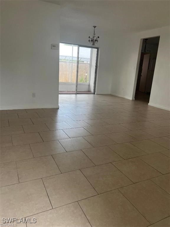 tiled empty room featuring a notable chandelier