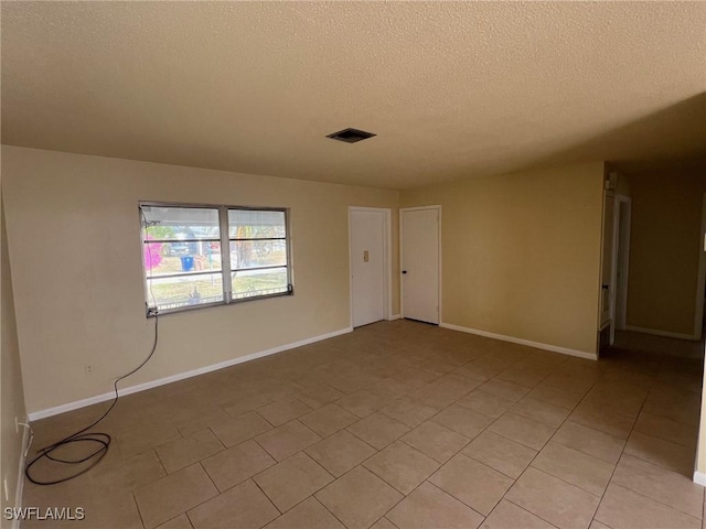 tiled empty room featuring a textured ceiling