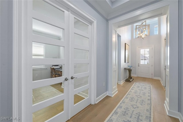 doorway to outside featuring a notable chandelier, plenty of natural light, and light hardwood / wood-style flooring