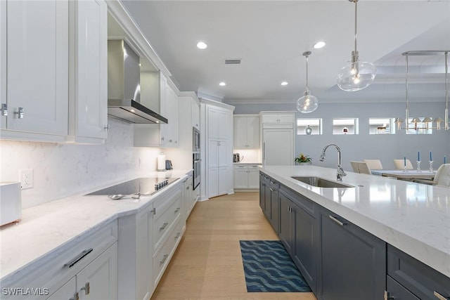 kitchen featuring pendant lighting, white cabinets, wall chimney range hood, sink, and appliances with stainless steel finishes