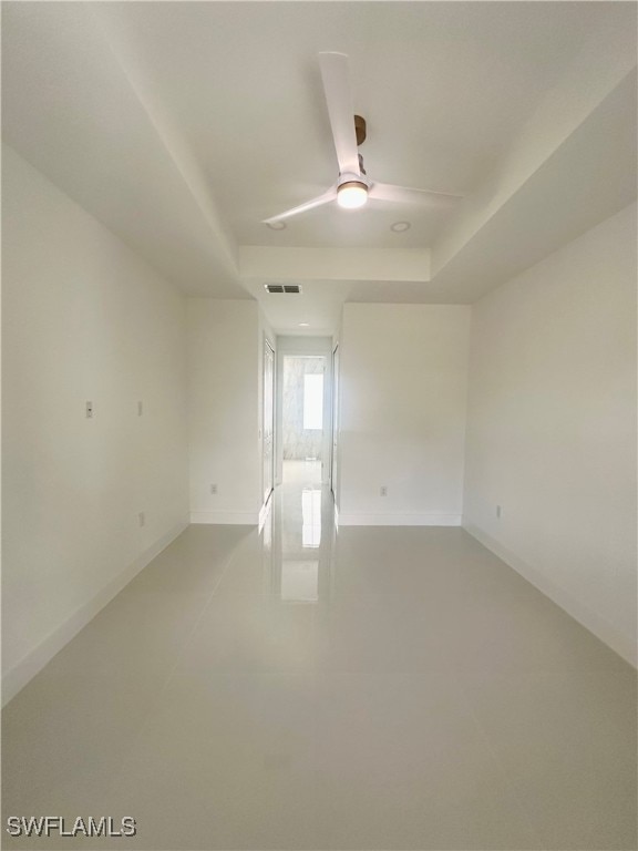 unfurnished room featuring ceiling fan and a raised ceiling