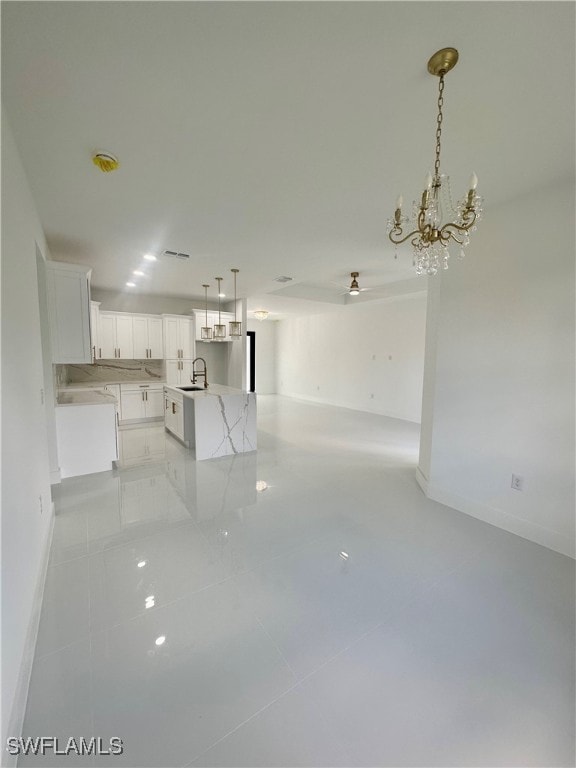 interior space featuring sink, light tile patterned floors, and ceiling fan with notable chandelier