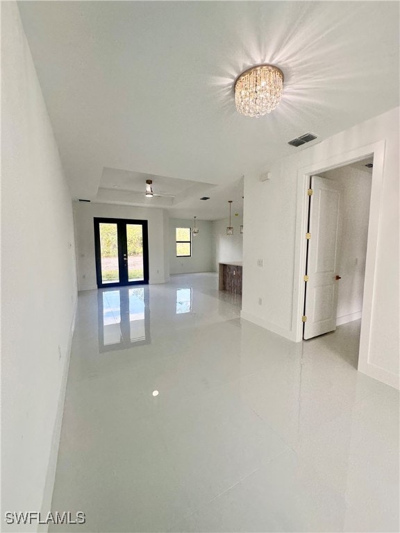 tiled empty room with french doors and ceiling fan with notable chandelier