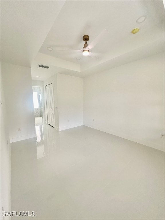 spare room featuring ceiling fan and a raised ceiling