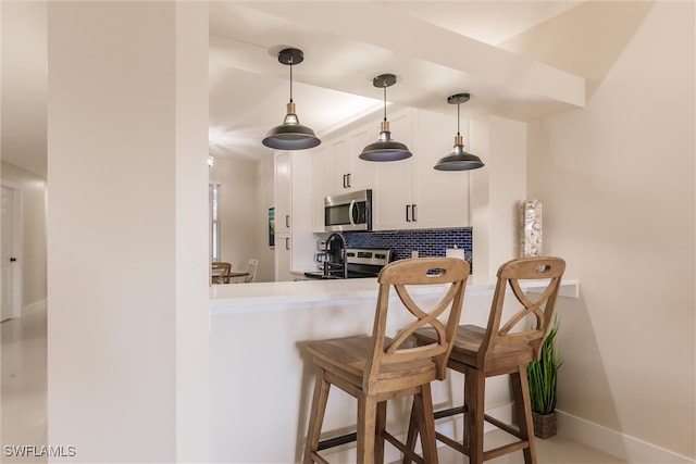 bar with stainless steel appliances, sink, backsplash, decorative light fixtures, and white cabinets