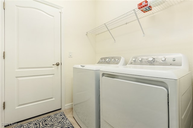 laundry area with washer and clothes dryer and light tile patterned flooring