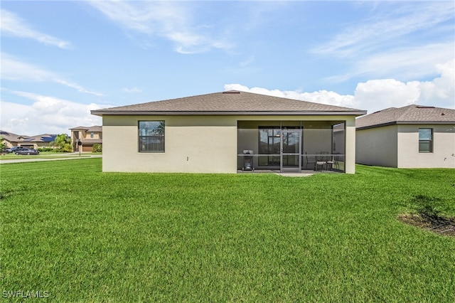 rear view of property featuring a lawn and a sunroom